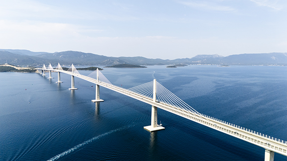 white suspension bridge over expanse of blue water